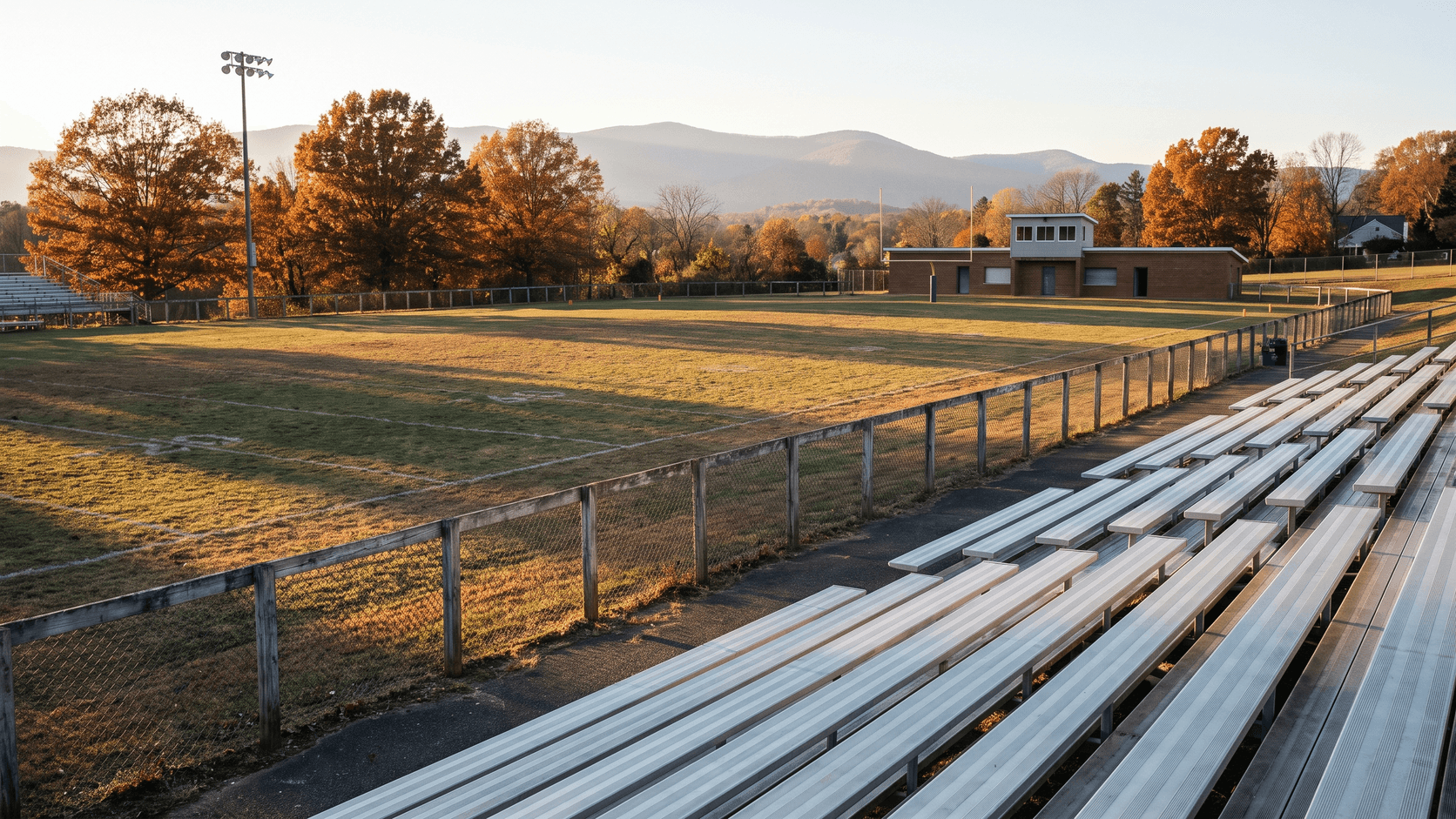 High school bleachers at late afternoon, Blue Ridge-inspired backdrop at the horizon