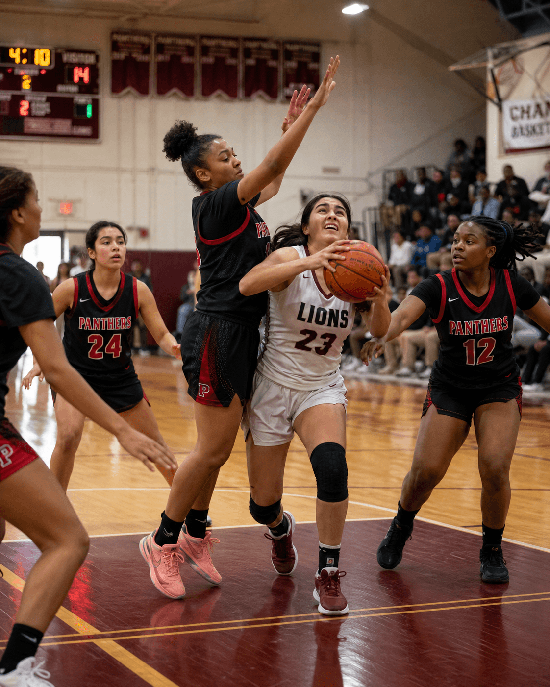Charlottesville-area girls basketball player driving to the rim against three defenders in a packed gym.